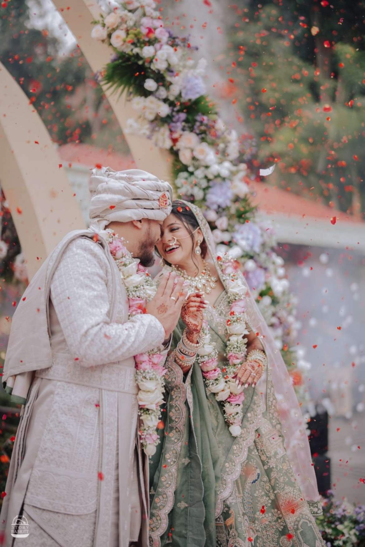 Bride and groom sharing an intimate moment under a floral mandap with petals falling — Shaadi Shenanigans